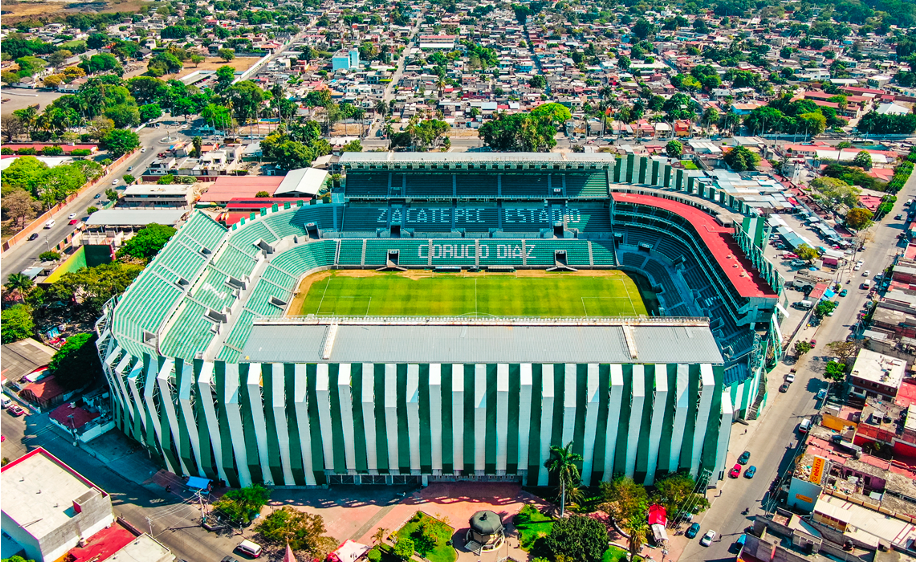 La imagen muestra un estadio de fútbol en una vista panorámica. Se observa la cancha cubierta de pasto y, en las gradas, una leyenda que dice: ZACATEPEC, ESTADIO CORUCO DÍAZ.